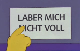Ausschnitt aus der Serie „Die Simpsons“. Der Busfahrer zeigt auf ein Schild, auf dem im Original steht: Nicht mit dem Busfahrer sprechen. Hier wurde der Satz geändert zu: Laber mich nicht voll.